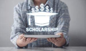 Person holding a tablet with a hologram displaying a graduation cap, dollar signs, and the word "SCHOLARSHIP.