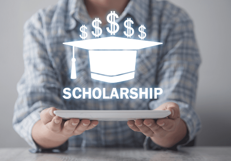 Person holding a tablet with a hologram displaying a graduation cap, dollar signs, and the word "SCHOLARSHIP.