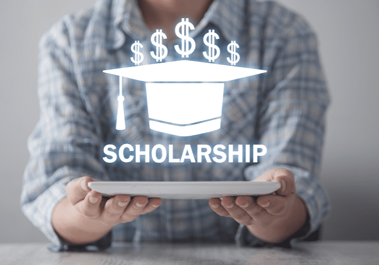 Person holding a tablet with a hologram displaying a graduation cap, dollar signs, and the word "SCHOLARSHIP.
