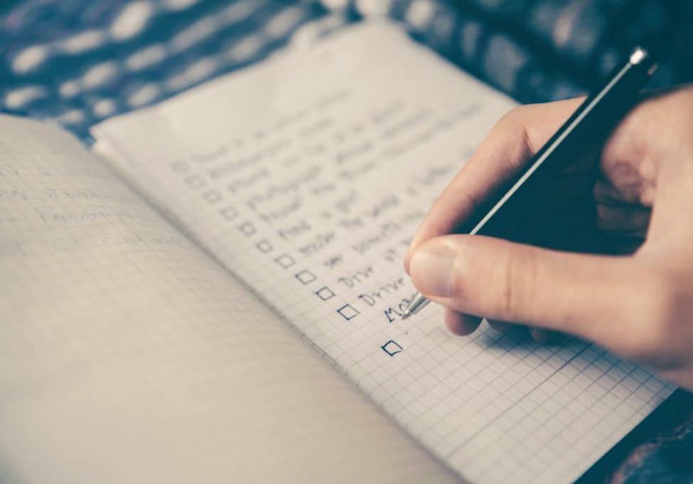 person writing bucket list on book